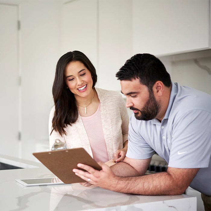 man showing clipboard to woman in kitchen