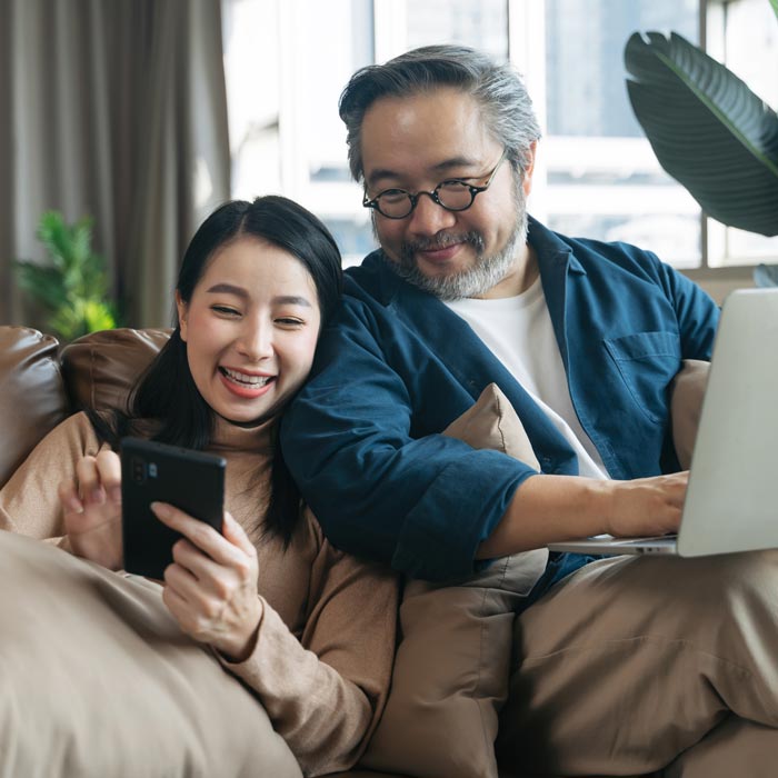 father and daughter looking at phone on couch